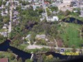 An aerial view of the area of the former Haggart Mills in Perth; Dam, front centre, in the original location; only the mill's foundation remains, beside dam; Haggart house and yard centre; Little Tay River across top; former Bolt Factory on the Little Tay centre. 2005